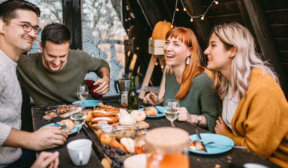 Group of four Gen Z sat around a table eating a meal together